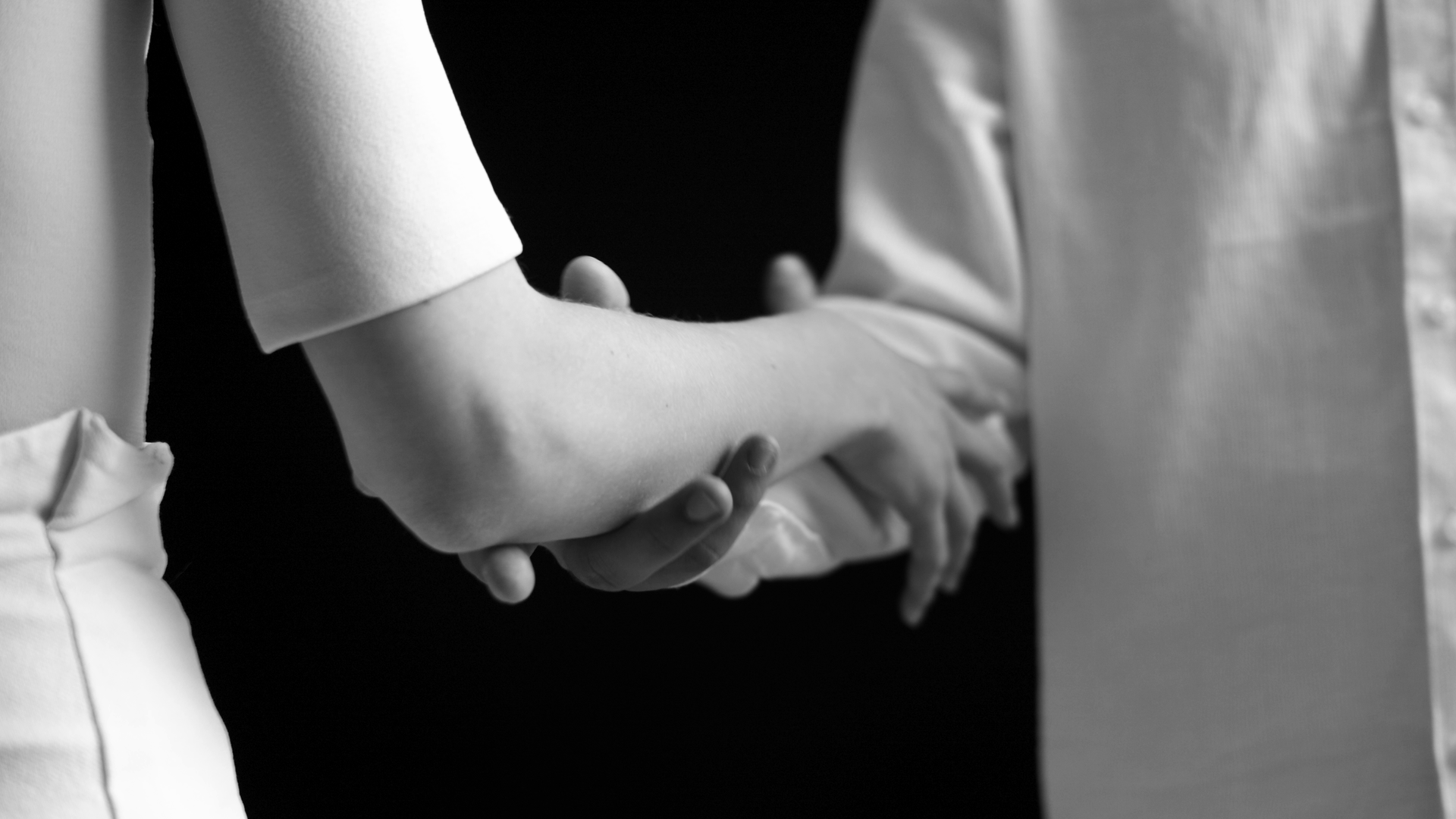 eszter galambos, Black and white image of two hands and arms holding each other. Studio background. 
