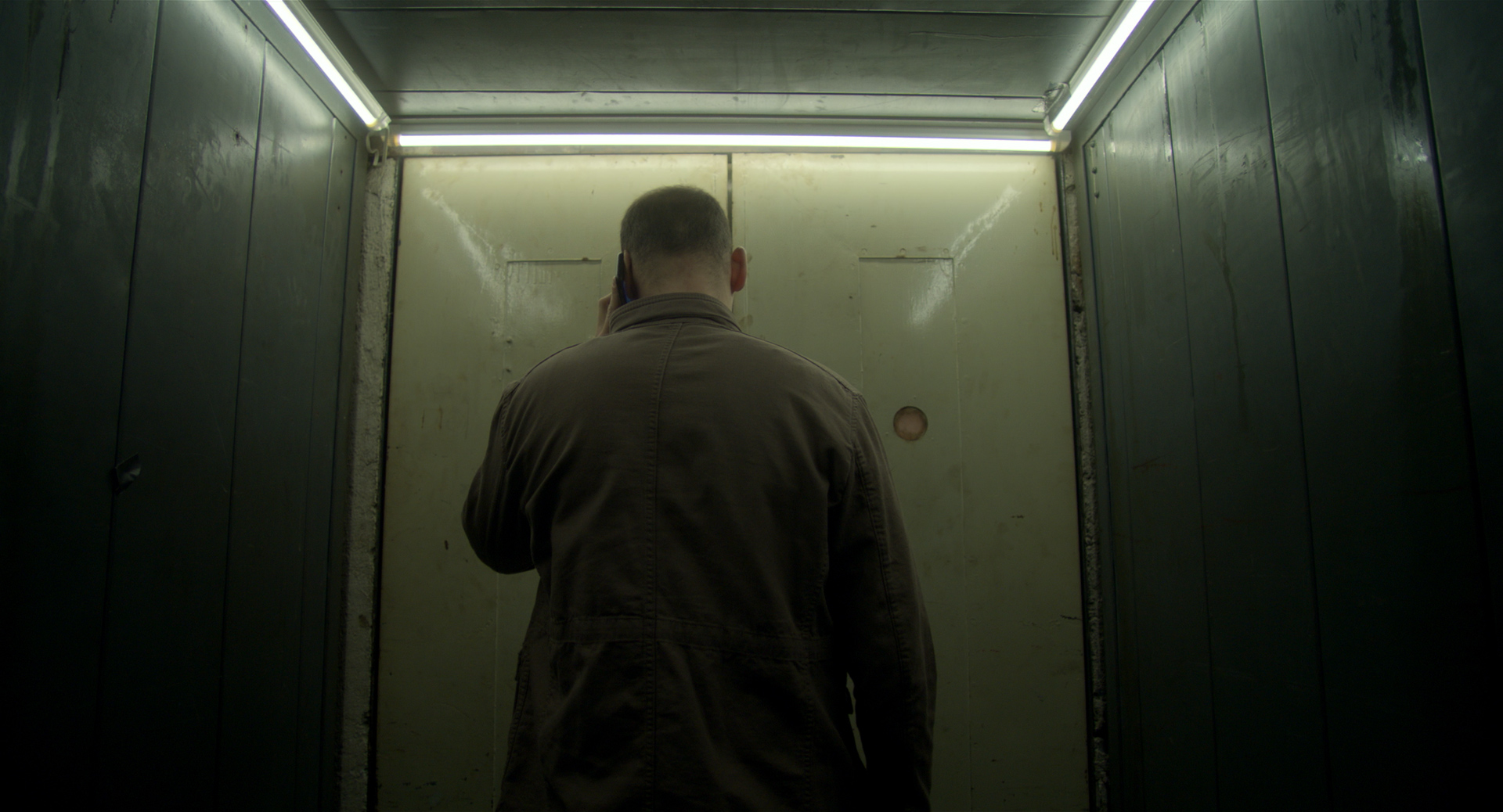 eszter galambos, Still from the short Tiger. Director of Photography, DOP, Cinematographer, operatőr: Eszter Galambos. Director: Péter Hajmási. Colorist: Anna Stalter, Cast: Milán SchruffIndustrial dirty, moody elevator. Somebody is talking on the phone. Green. Cinematographer: Galambos Eszter. Diector: Péter Hajmási