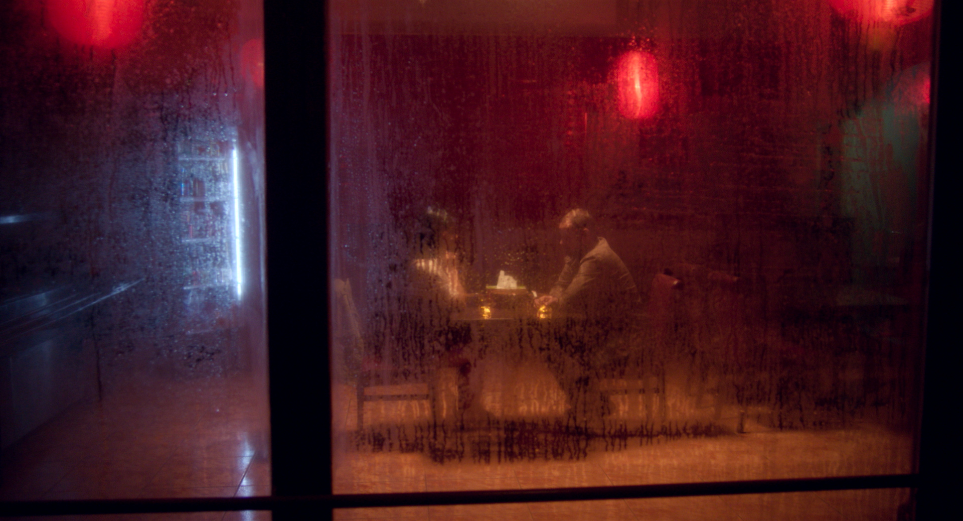 eszter galambos, Still from the short Tiger. Director of Photography, DOP, Cinematographer, operatőr: Eszter Galambos. Director: Péter Hajmási. Colorist: Anna Stalter, Cast: Milán SchruffChinese restaurant at night. Atmospheric look. Moody environment. Man and women sitting there. Still from a short film called Tiger. Director of Phototgraphy: Eszter Galambos
